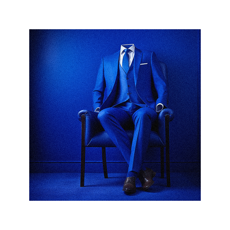 A man in a blue suit sitting in a chair.