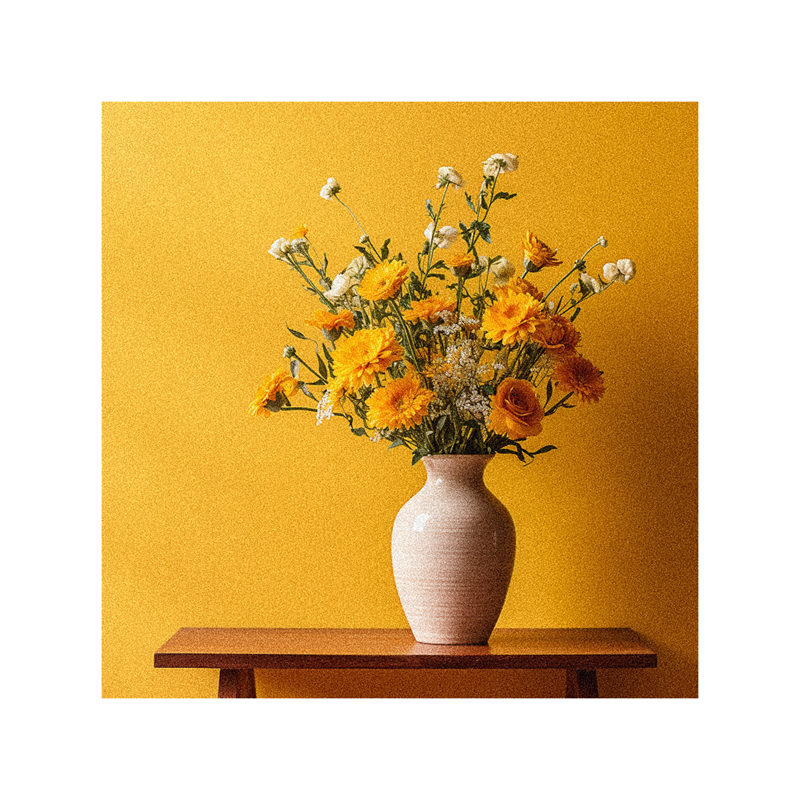 A vase of flowers on a table in front of a yellow wall.