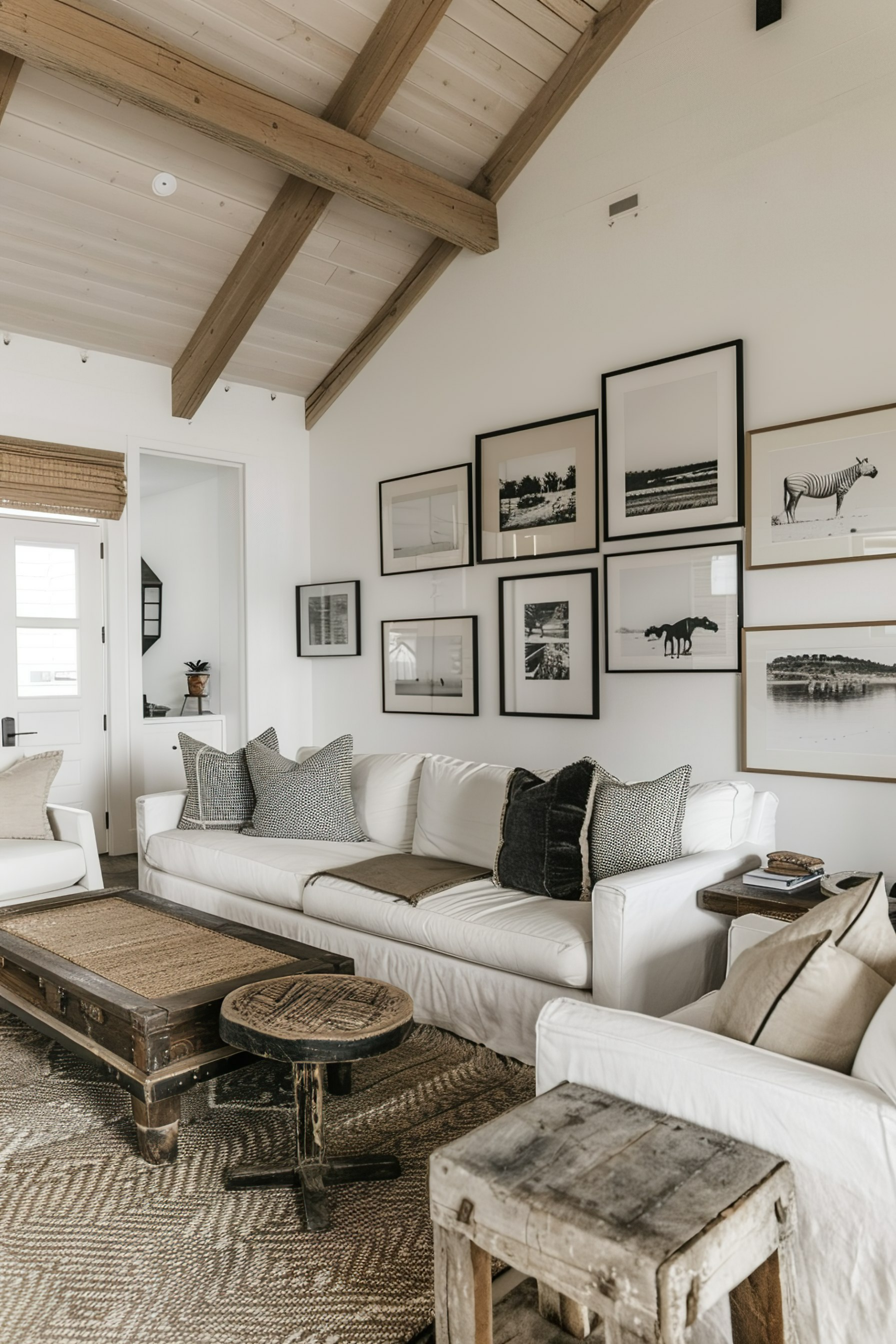 Cozy living room with white couch, wooden beams, and gallery wall of monochrome nature photos.