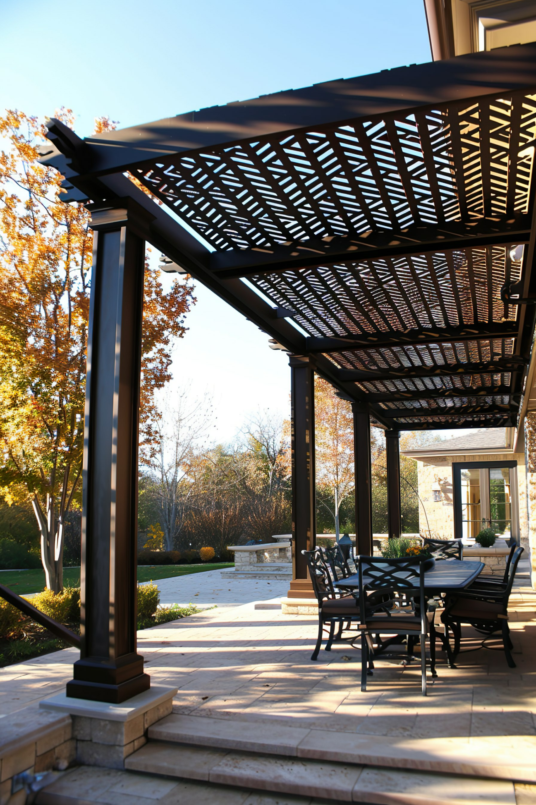 Elegant patio area with a pergola, outdoor dining set, and autumn trees in the background.