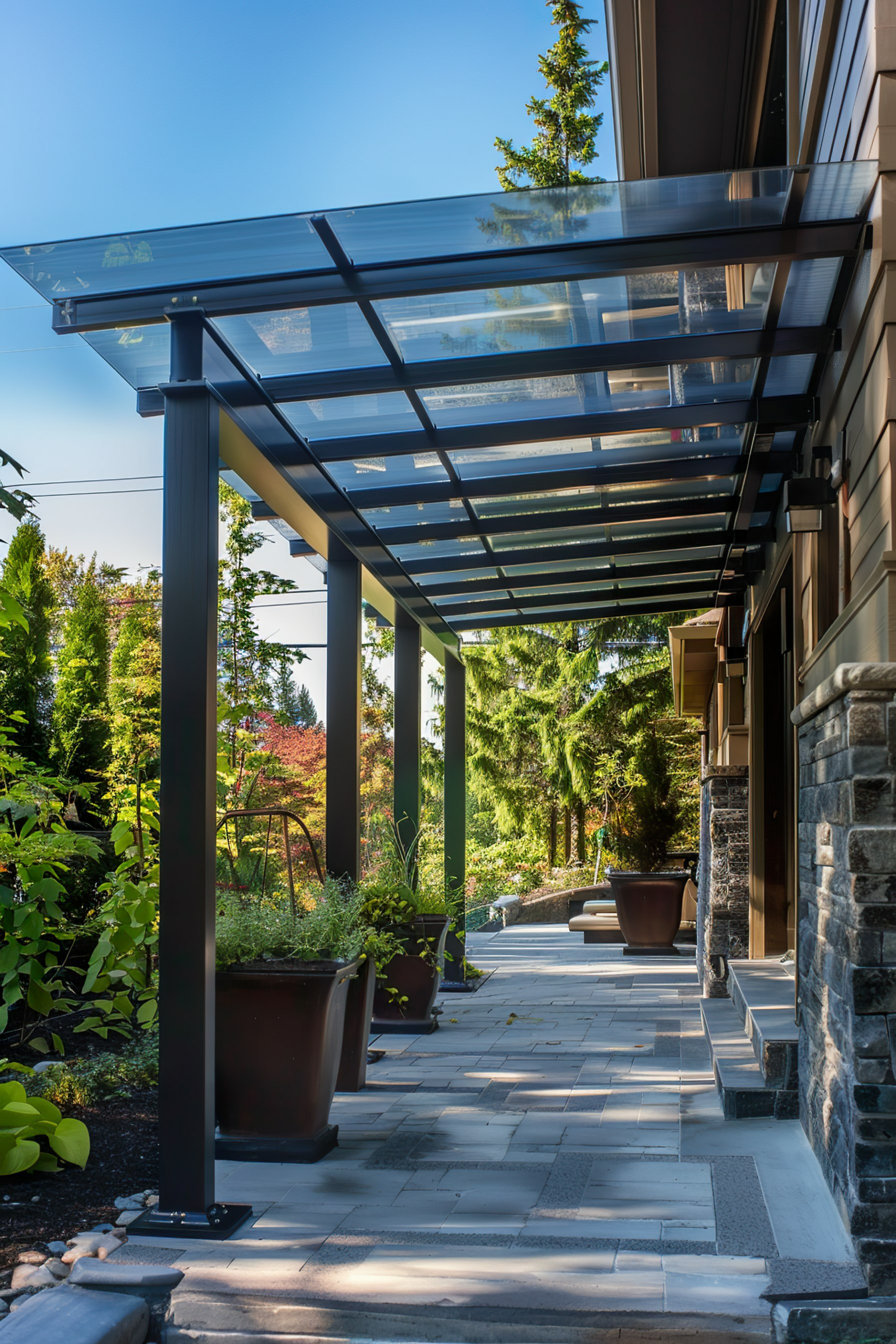 Side view of a modern home's covered walkway with translucent roof panels, flanked by stone walls and landscaped garden.