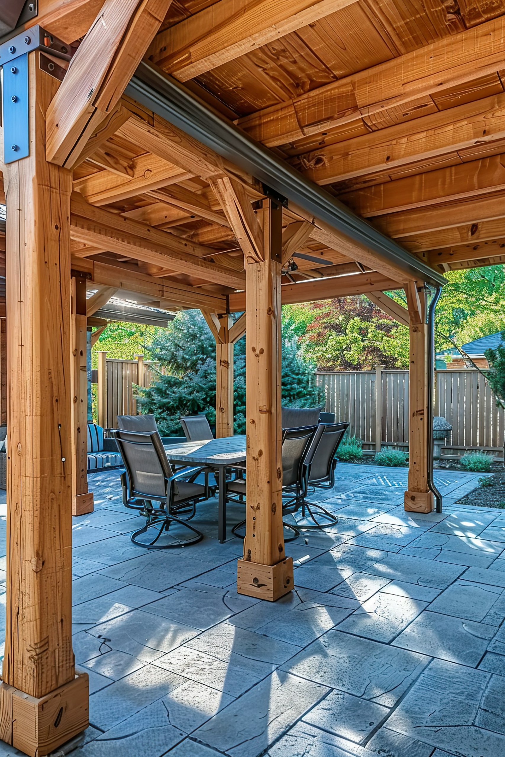 Wooden pergola over a patio with a dining table and chairs set in a sunny backyard garden.